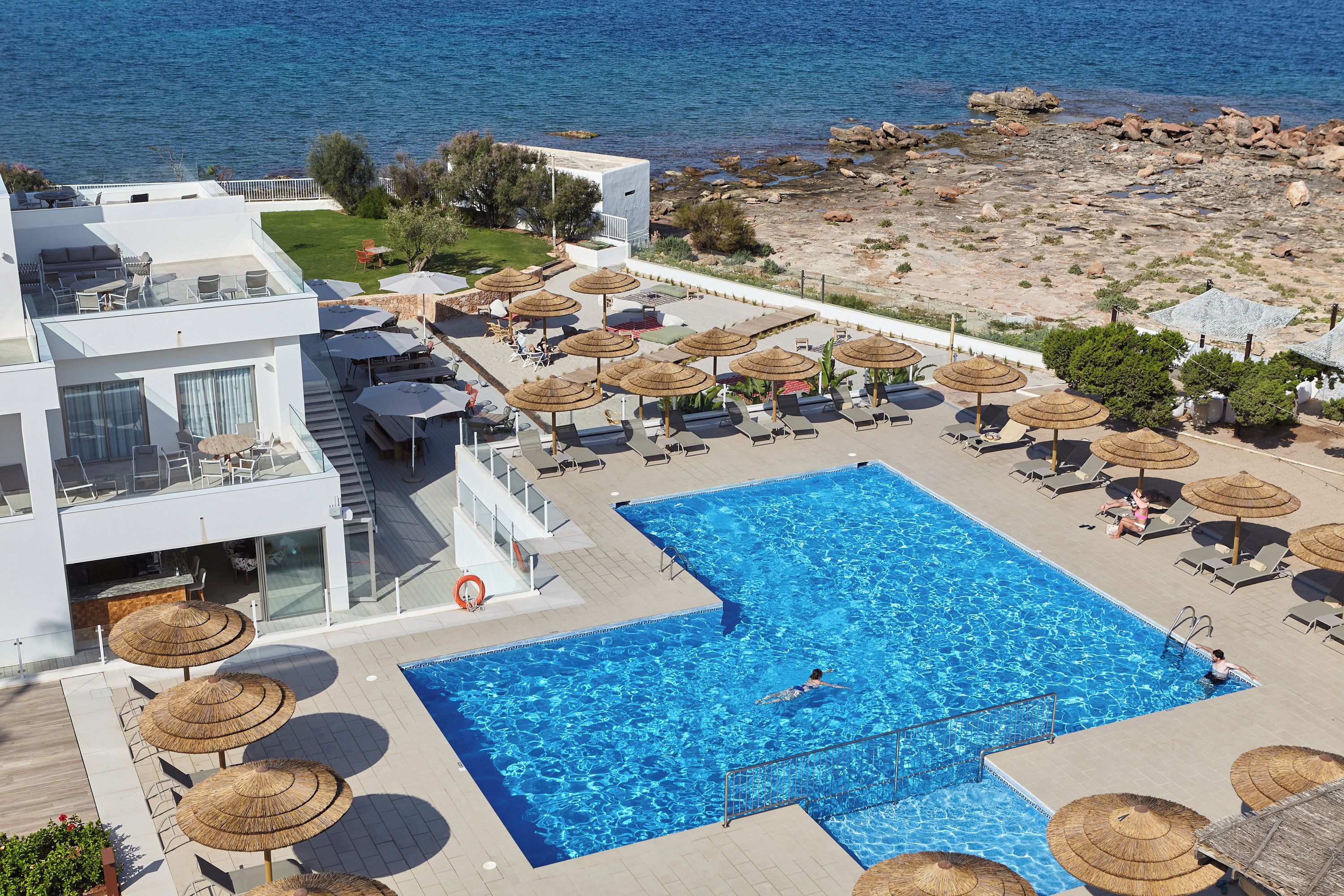 A resort with a swimming pool, sun loungers, and umbrellas.