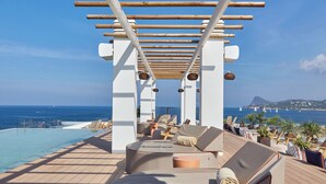 A sunlit outdoor lounge area with a pool, wooden pergola, and ocean views. - Can Salia (Sant Josep de sa Talaia)