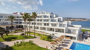 A modern hotel with multiple floors, a swimming pool, and a view of the sea. - Can Salia (Sant Josep de sa Talaia)