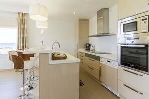 A modern kitchen with a central island, bar stools, a Bosch microwave, and a coffee maker. - Can Salia (Sant Josep de sa Talaia)