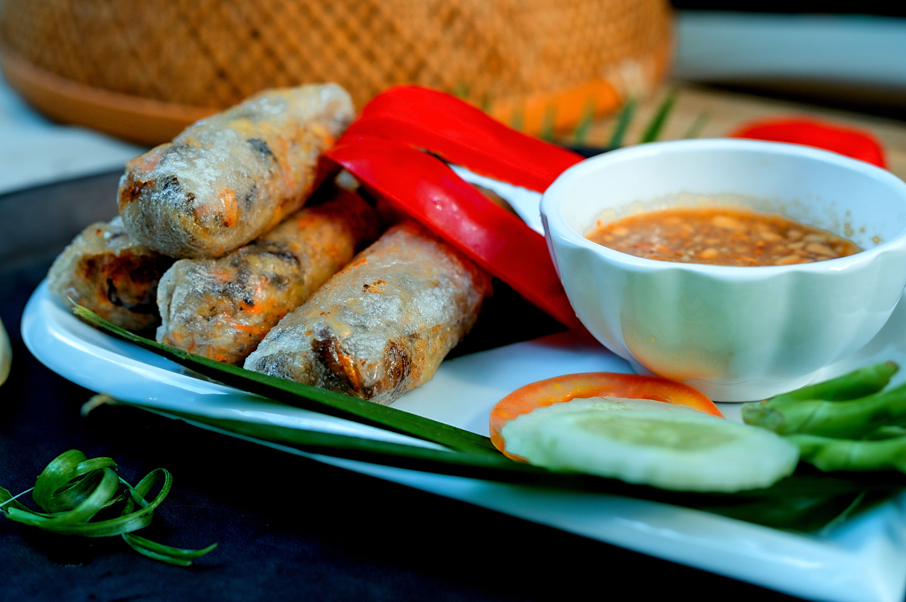 Un plato de rollitos primavera con salsa para mojar y verduras frescas.