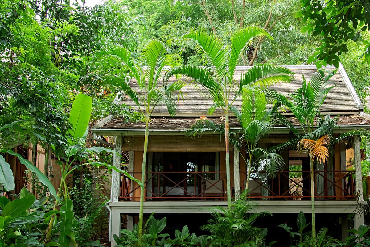 Une maison à deux étages, entourée d’une végétation luxuriante.
