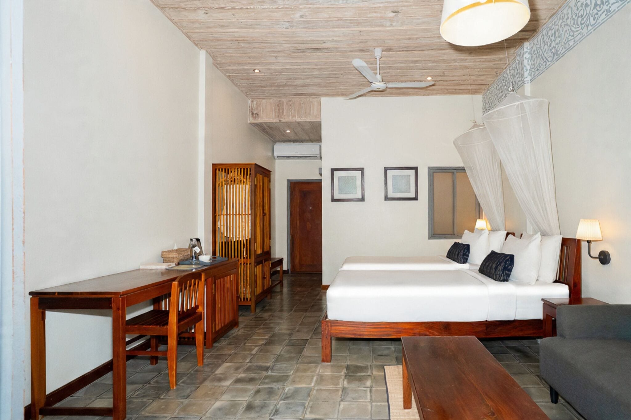 Una habitación con cama, escritorio, silla, mesa y ventilador de techo.