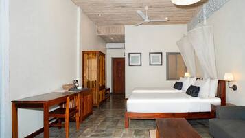 Una habitación con cama, escritorio, silla, mesa y ventilador de techo.