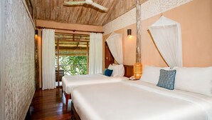 Un dormitorio con techo de madera, cama con ropa de cama blanca, mesita de noche con lámpara y ventana con cortinas.