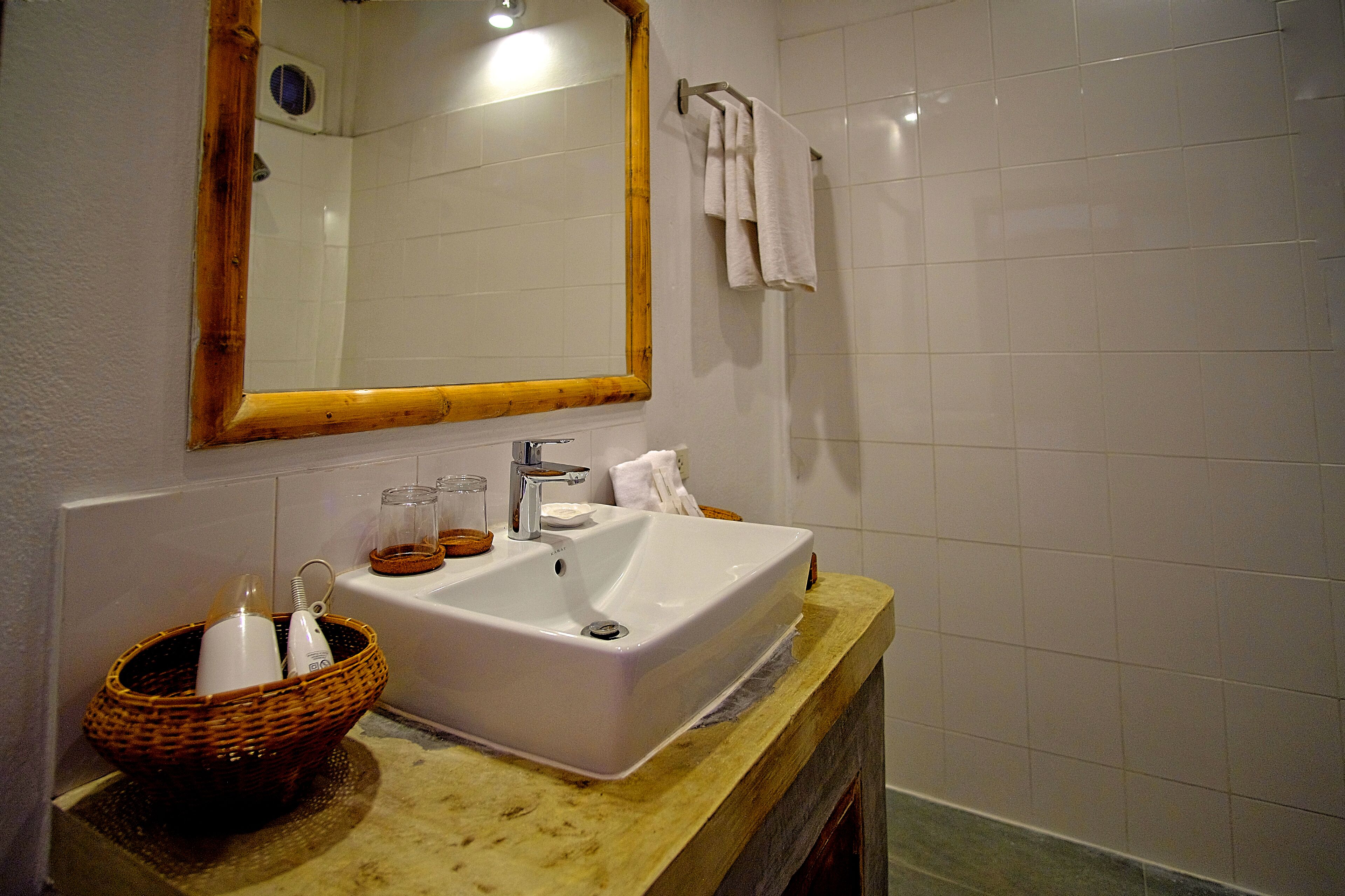 Une salle de bain avec un lavabo blanc, un miroir encadré en bois et un porte-serviettes.