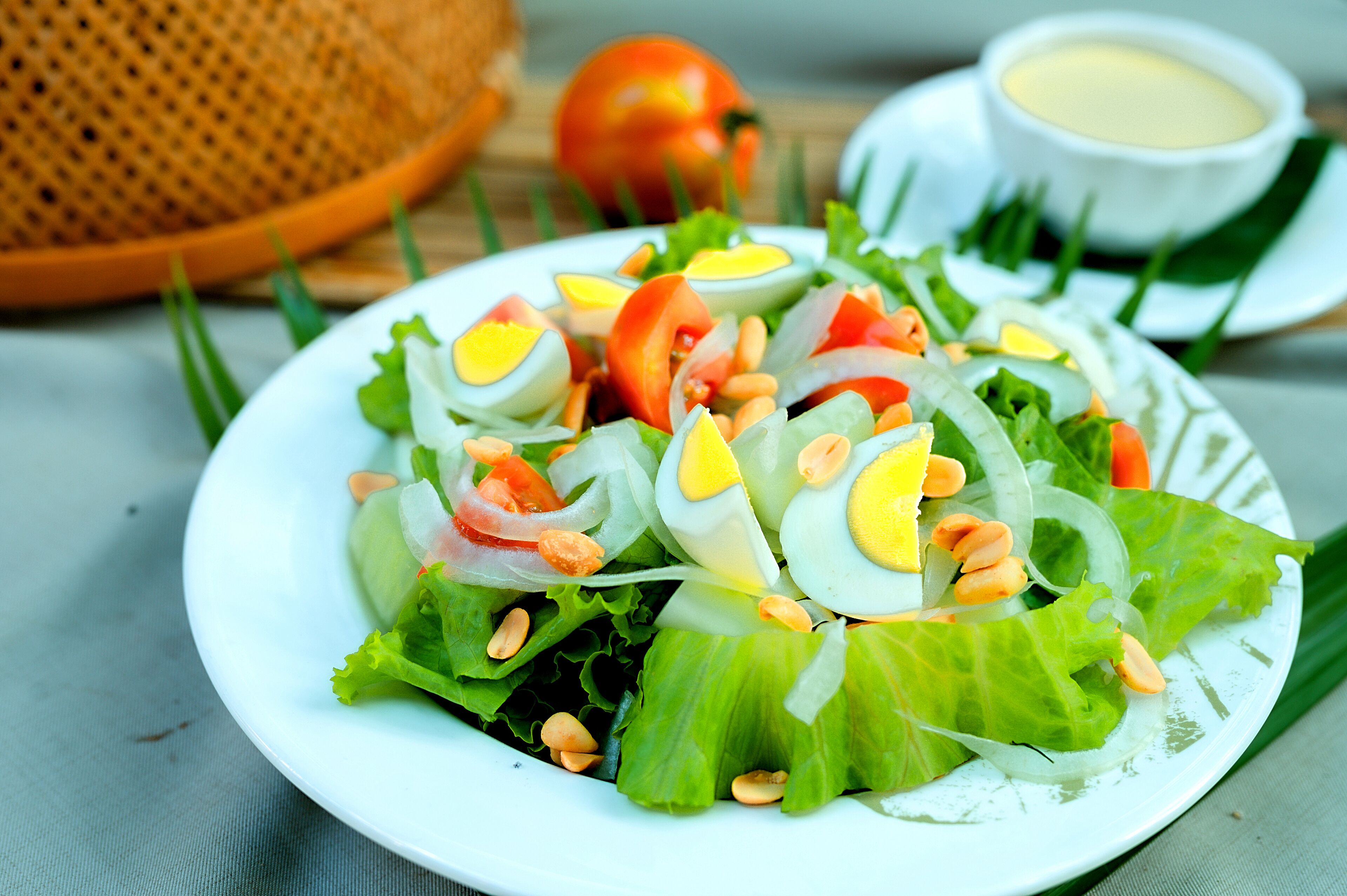 A plate of salad with lettuce, tomatoes, boiled eggs, and nuts.