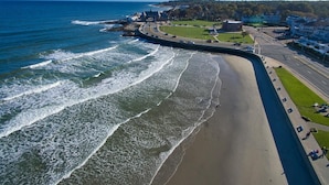 A coastal road with a beach on one side and a town on the other. - The Shore House (Narragansett)