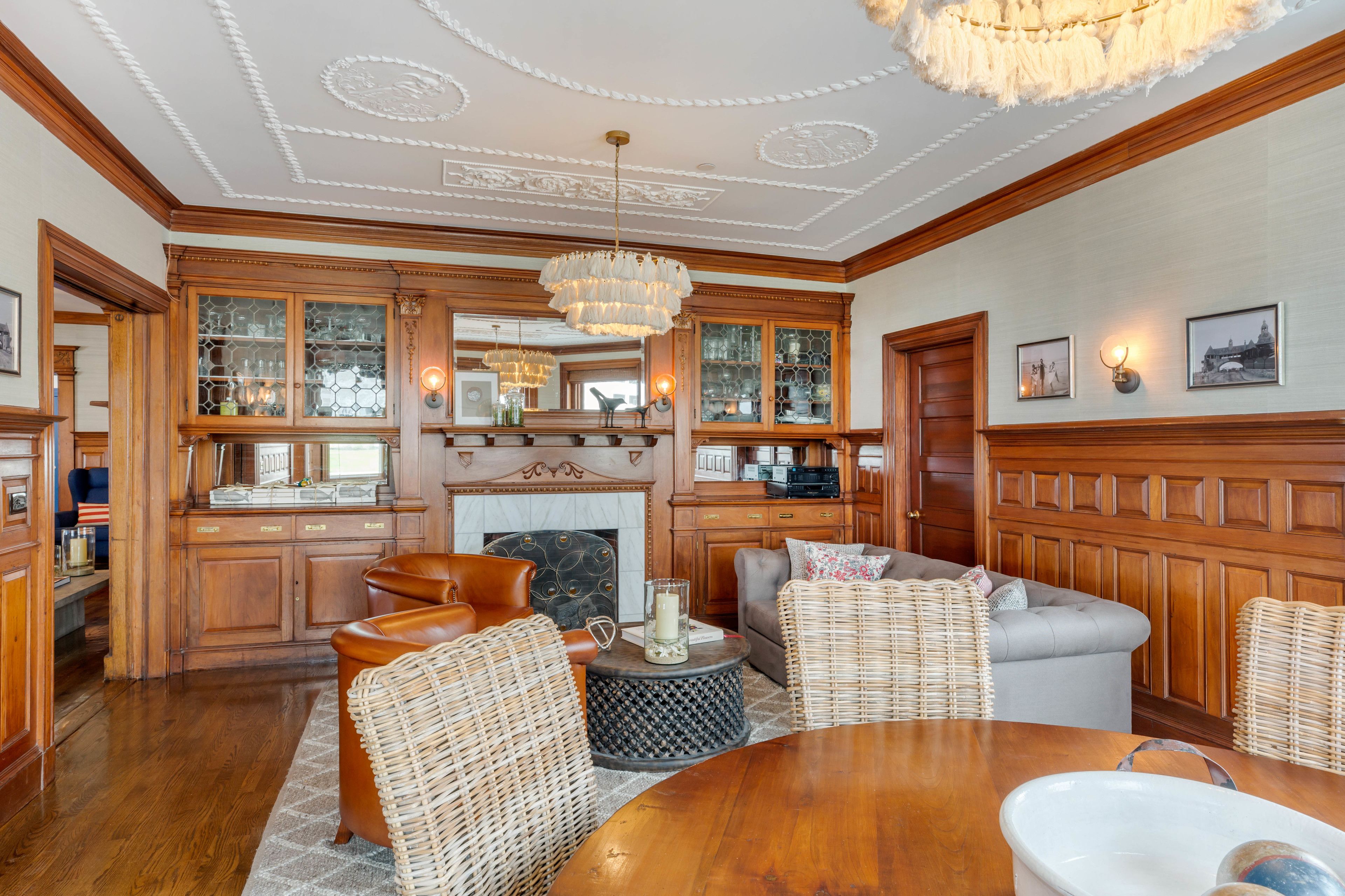 A spacious living room with a wooden floor, a fireplace, and a large chandelier.
