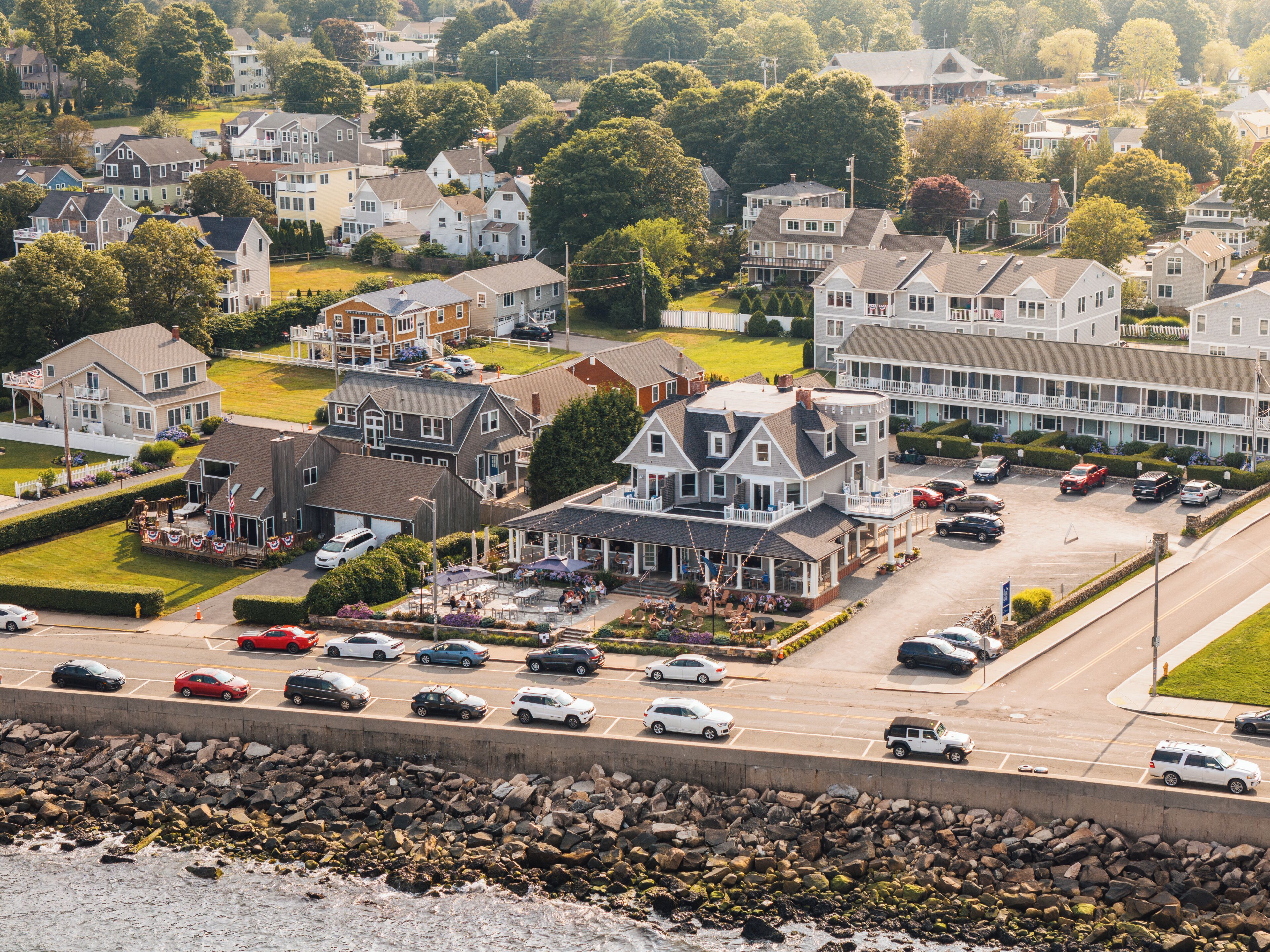 A coastal town with a prominent hotel featuring a large porch and outdoor seating area.