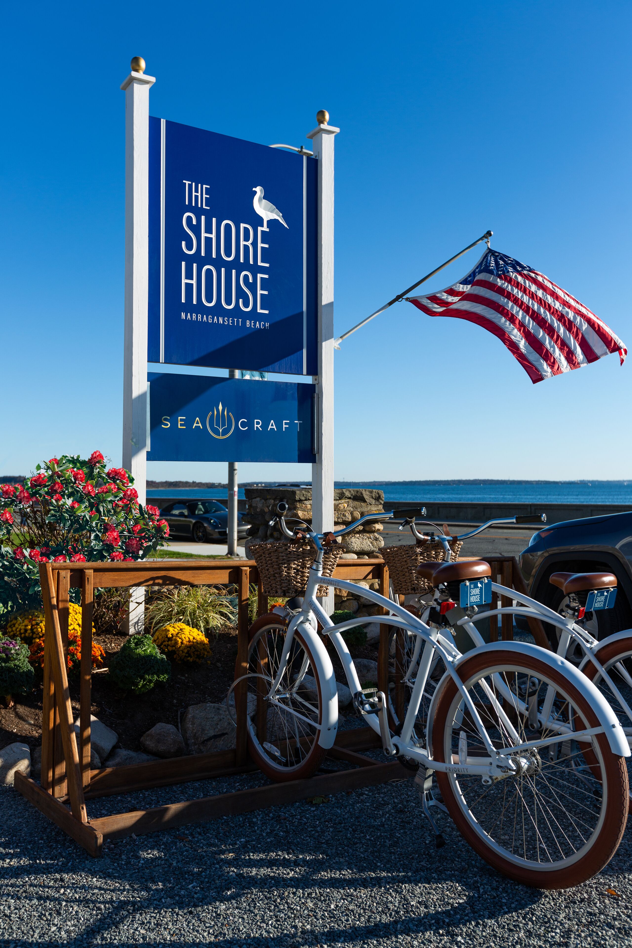 A sign for The Shore House with a seagull logo, an American flag, and bicycles.