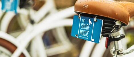 Une rangée de vélos, avec une pancarte bleue indiquant qu’ils sont à louer et portant l’inscription « The Shore House ».