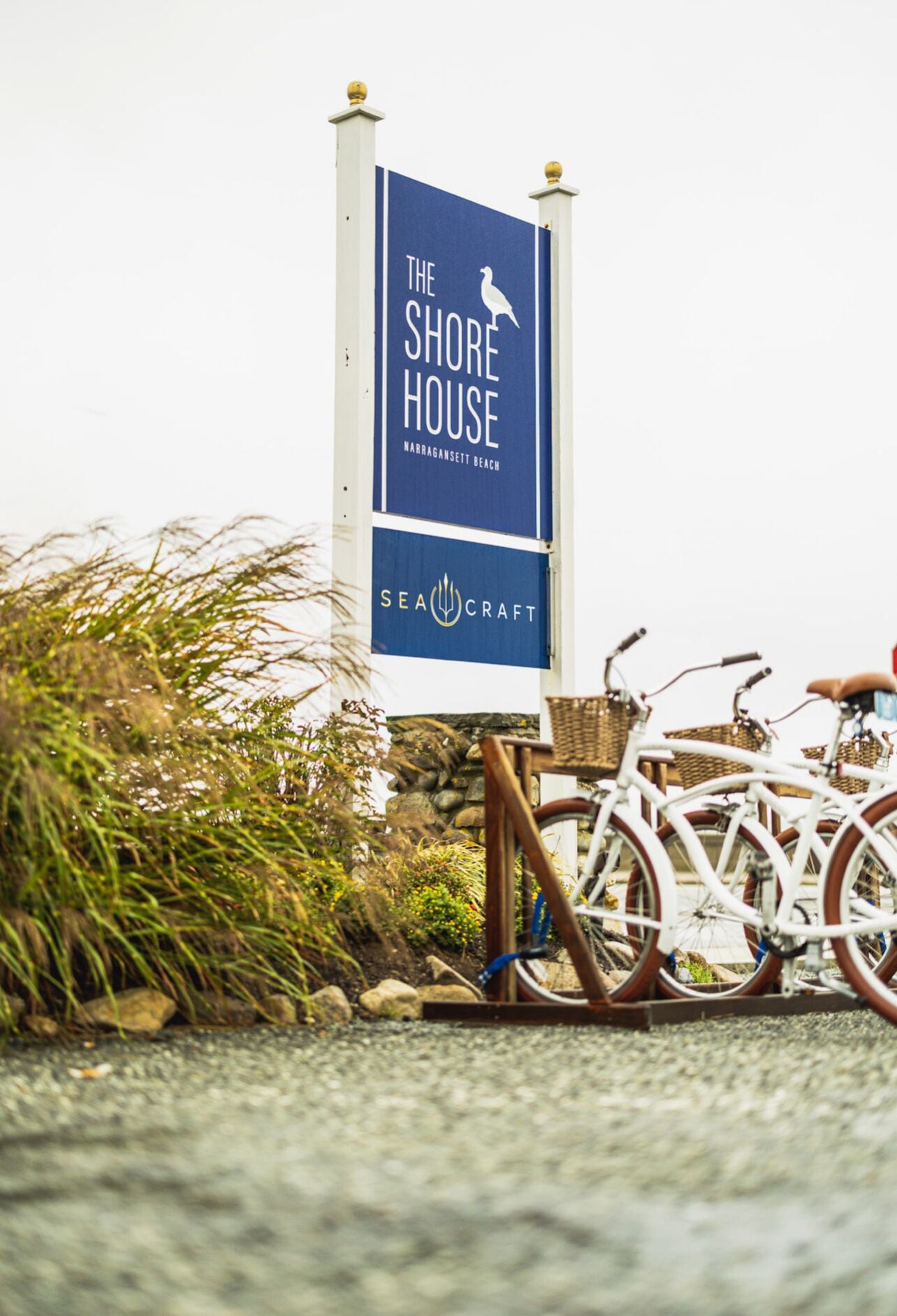 Schild für 'The Shore House' mit einem Möwen-Logo, das ein Küstenmotiv andeutet, und ein Fahrrad in der Nähe.