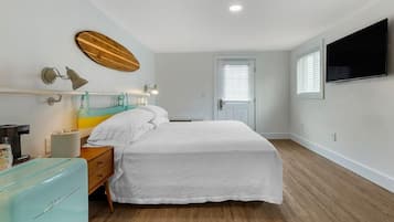 A bedroom with a bed, bedside table, lamp, and a television on the wall.