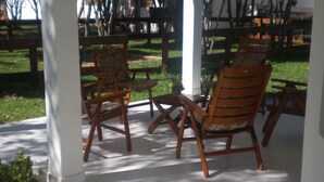 A covered patio area with wooden chairs and a tiled floor. - Ruta del Sol (San Bernardino)