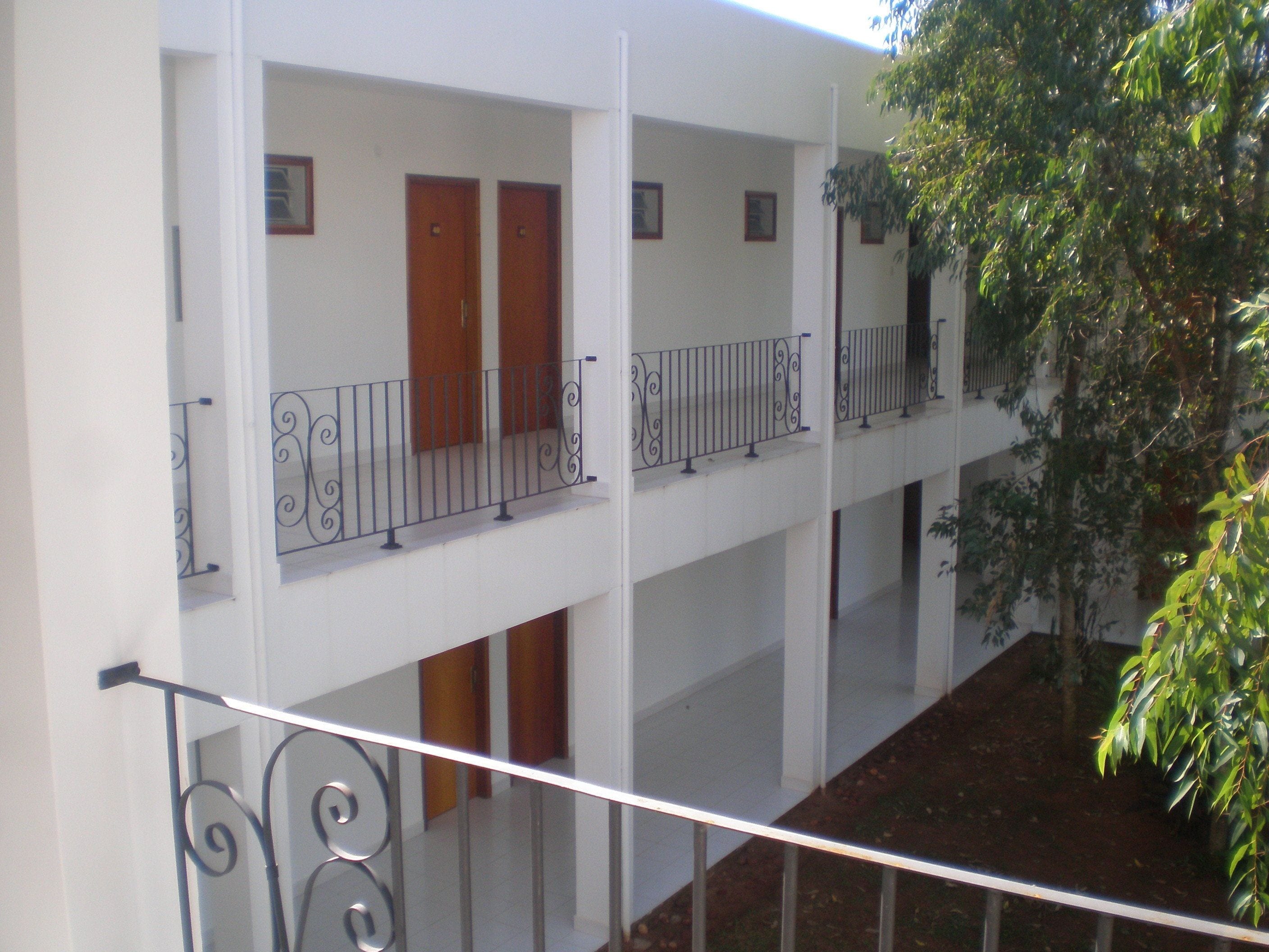 A multi-level building with balconies, wooden doors, and metal railings.