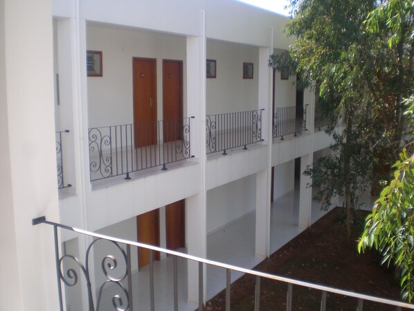 A multi-level building with balconies, wooden doors, and metal railings.