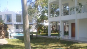 A multi-story building with a swimming pool, surrounded by grass and trees. - Ruta del Sol (San Bernardino)