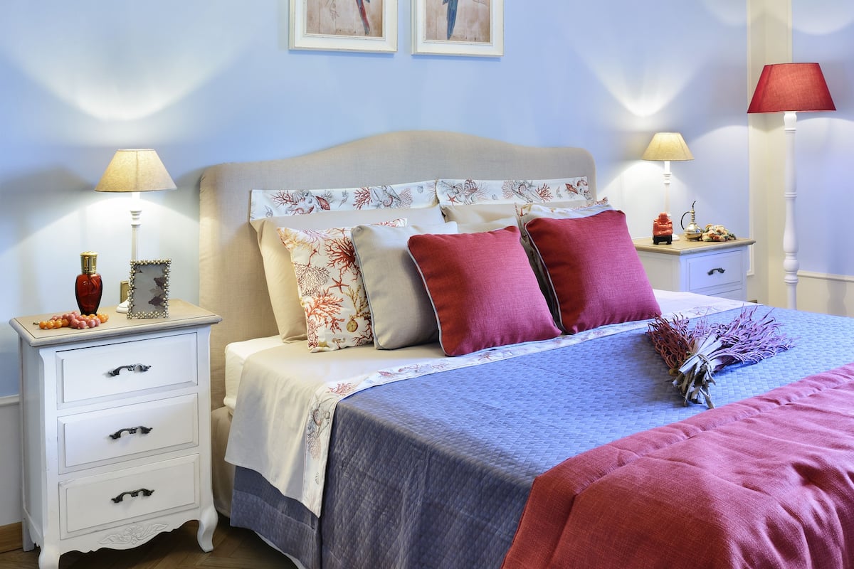 A neatly arranged bedroom with a bed, two nightstands, a dresser, and two wall-mounted lamps.
