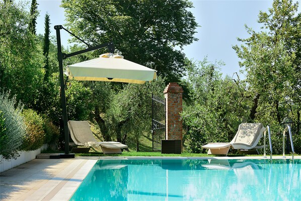 A swimming pool with two lounge chairs and a canopy.