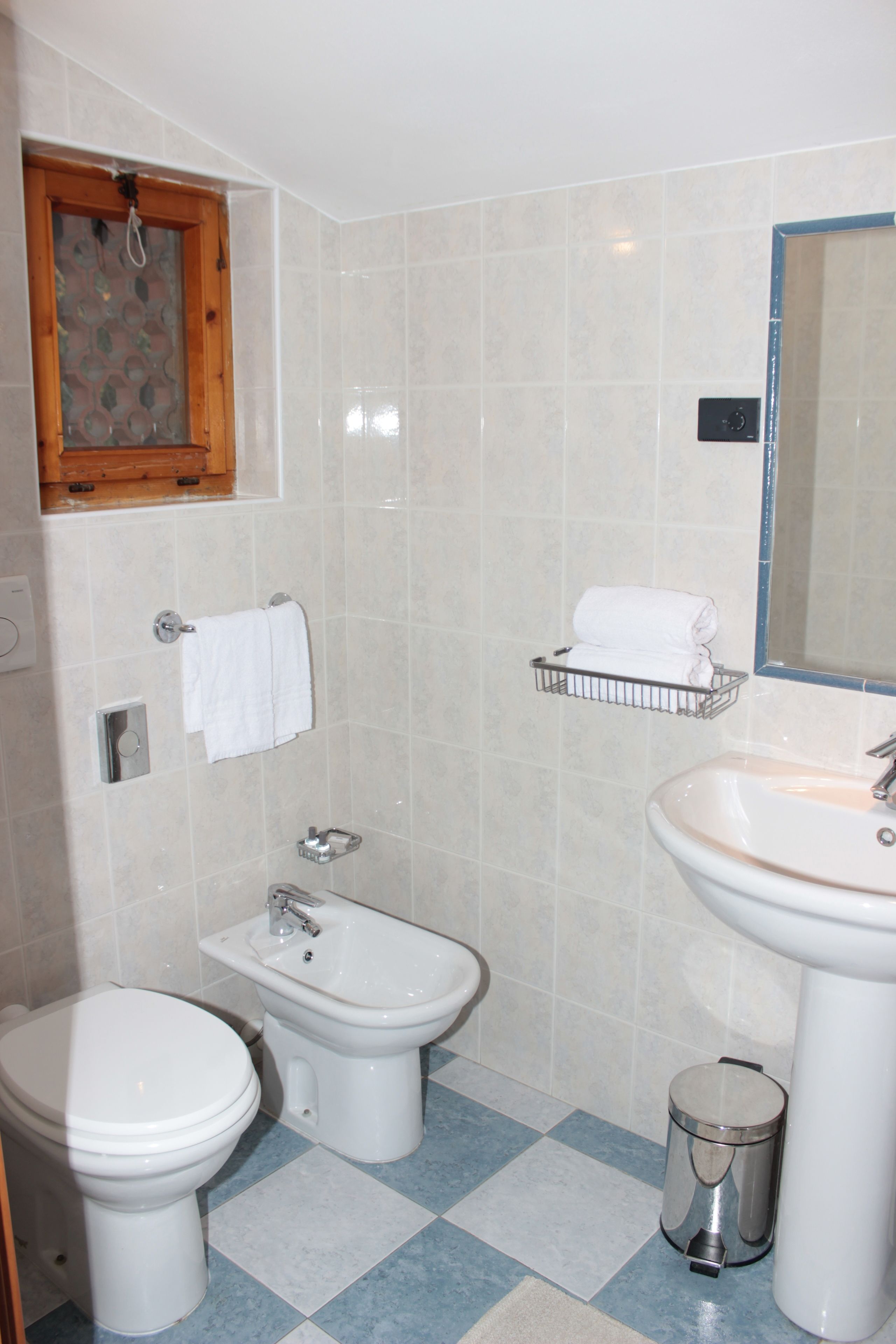 Une salle de bain équipée de toilettes, d’un bidet, d’un lavabo et d’une petite poubelle.