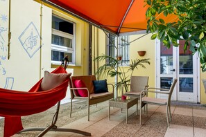 A cozy outdoor seating area with wicker furniture, a hammock, and potted plants. - Ostello San Filippo Neri (Modena)