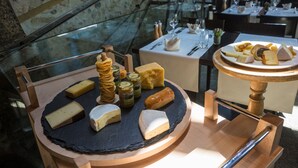 A cheese board with various cheeses and crackers, set on a wooden stand in a restaurant. - Stiftung Kartause Ittingen (Warth-Weiningen)