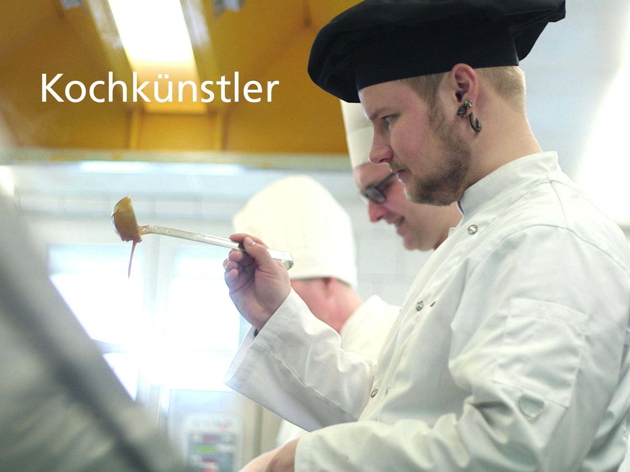 Koks in een keuken, met de tekst 'Kochkunstler' zichtbaar.