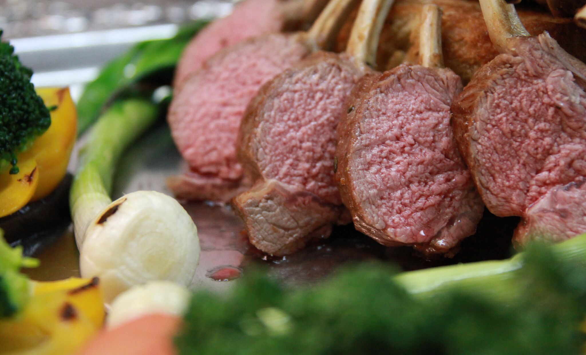 Une vue rapprochée d’un plat de viande cuite accompagné de légumes.