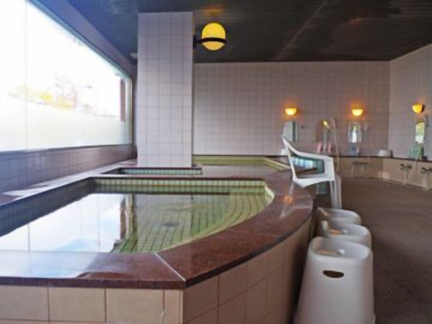 A swimming pool with a curved edge, a white chair, and a trash bin.