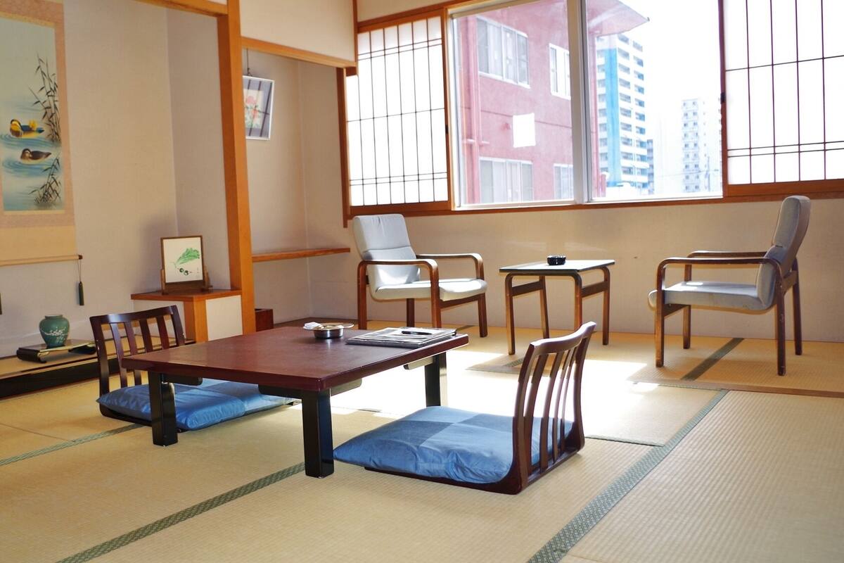 Una habitación japonesa tradicional con suelo de tatami, una mesa baja y asientos.