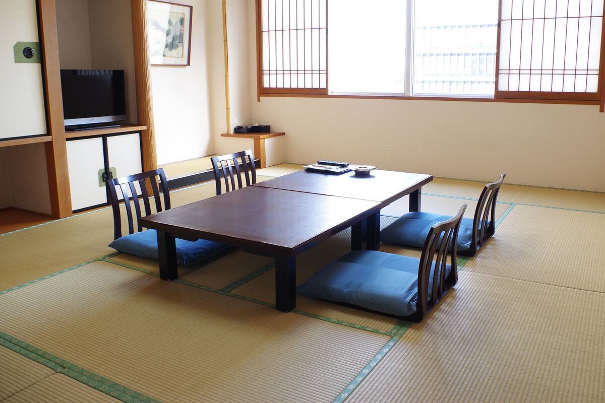 Una habitación japonesa tradicional con suelo de tatami, una mesa baja y sillas de madera.