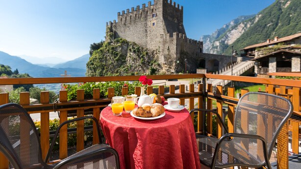 A table with breakfast items and a view of a castle. - Hotel Antica Croce (Tenno)