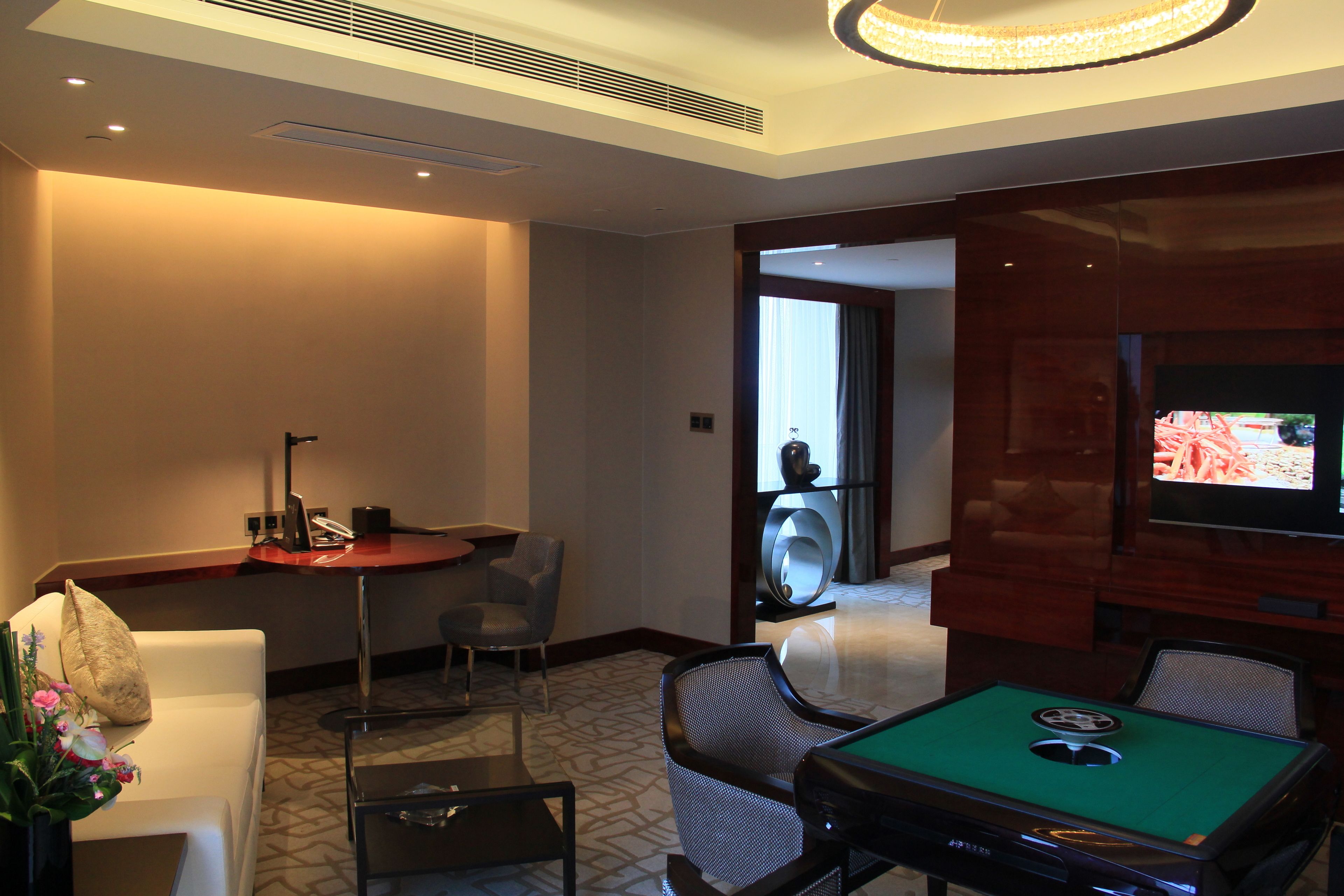 A hotel room with a pool table, a television, a desk, and a seating area.
