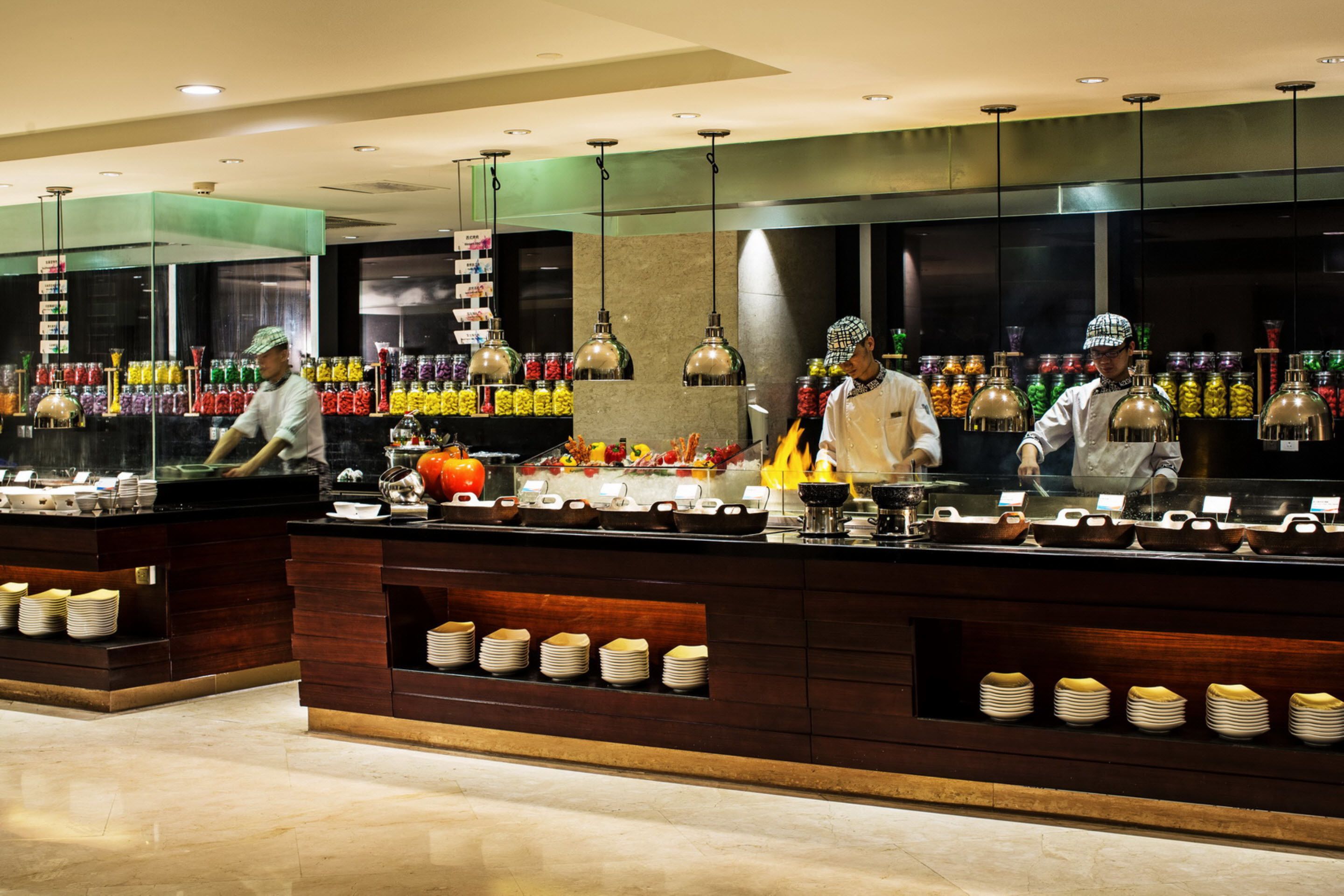 A buffet area with multiple food stations, a variety of dishes, and a counter with staff serving.