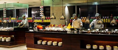 A buffet area with multiple food stations, a variety of dishes, and a counter with staff serving.