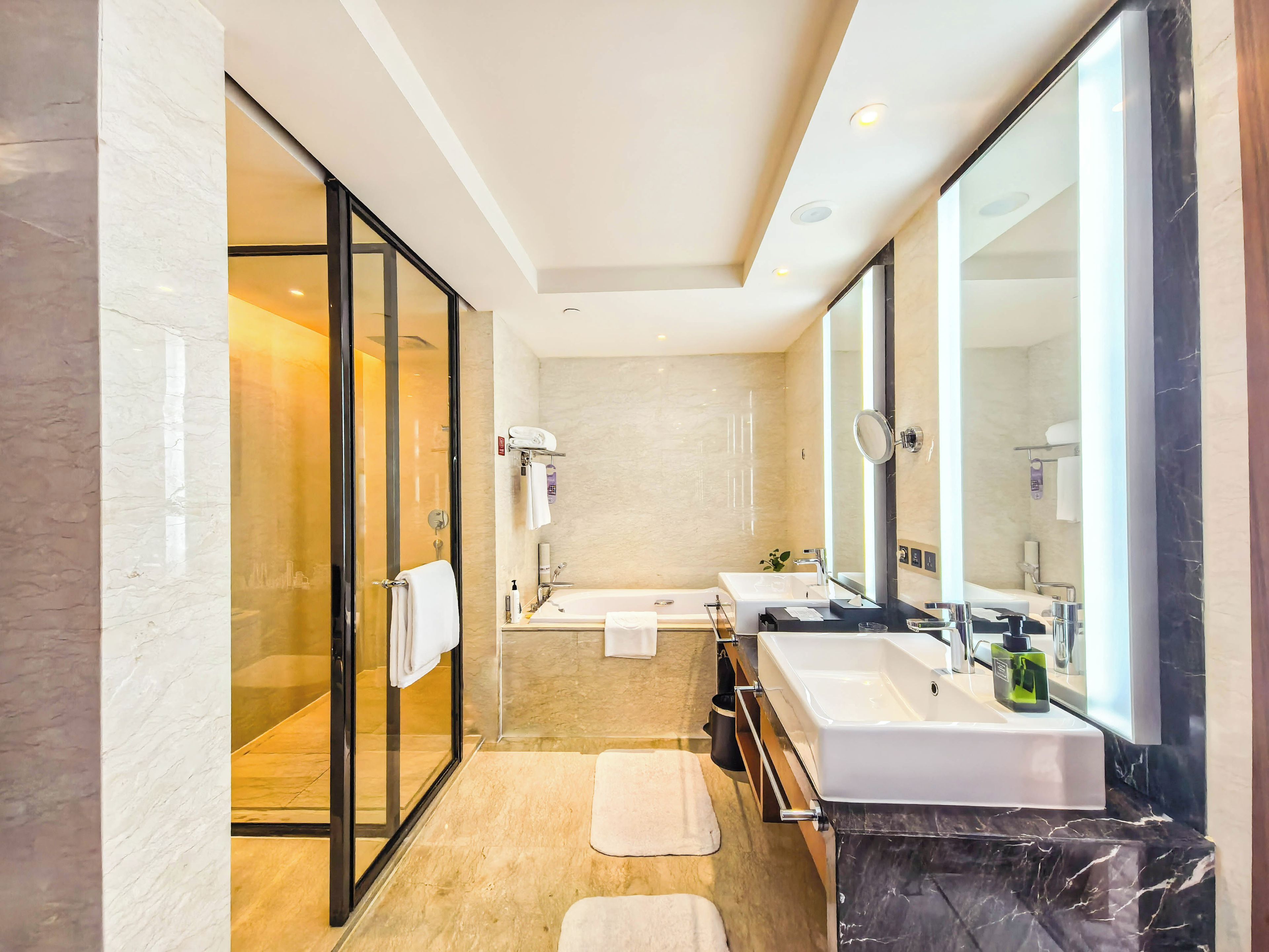 Une salle de bain moderne avec une douche à parois de verre, un grand miroir et un meuble-lavabo.