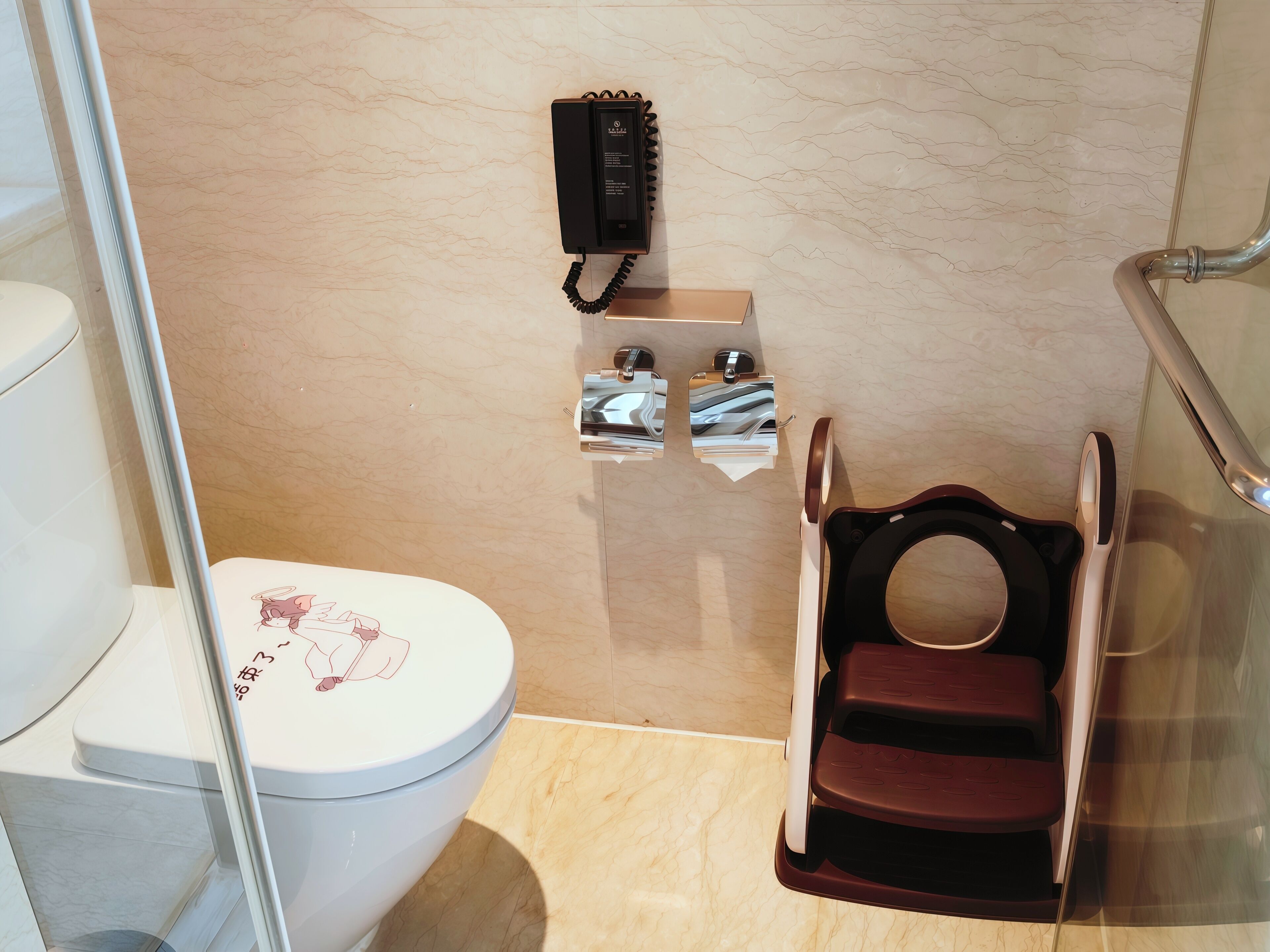 Un baño con inodoro, bidé, secador de manos y teléfono.
