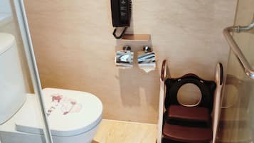 Un baño con inodoro, bidé, secador de manos y teléfono.