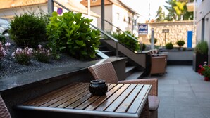 An outdoor seating area with wicker furniture and a table with a black pot. - Felicity Garni Hotel (Bratislava)