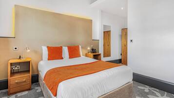 Une chambre d’hôtel moderne avec un grand lit, une table de chevet, une commode et une armoire.