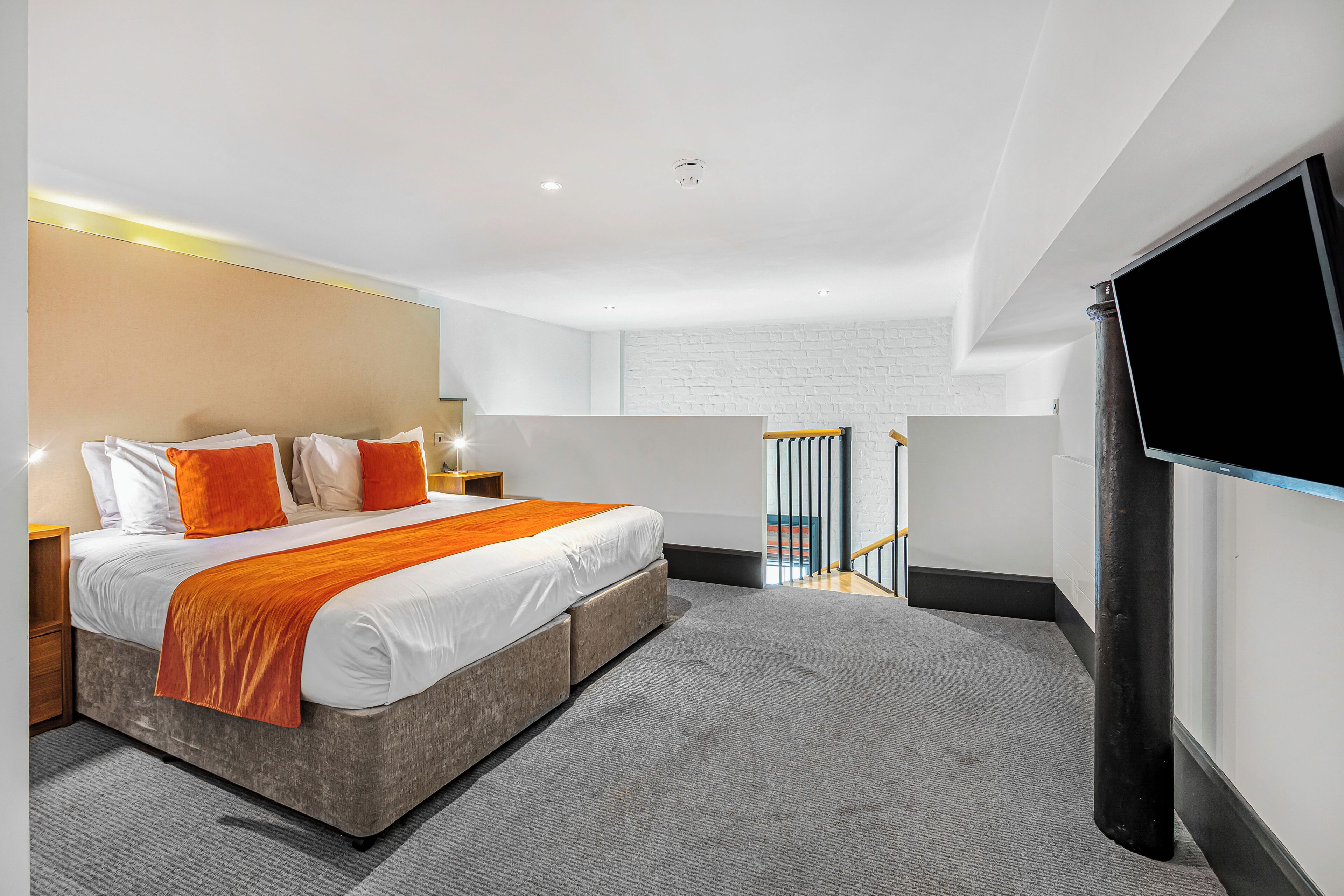 A modern hotel room with a large bed, a flat-screen TV, and a view of the hallway.