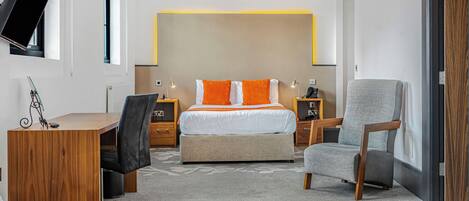 Una habitación de hotel moderna con una cama grande, un escritorio, una silla y un televisor montado en la pared.