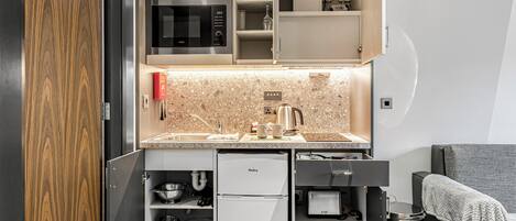 A compact kitchen with a microwave, sink, and a built-in refrigerator.