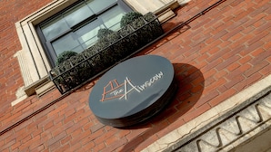 A brick building with a circular sign that reads "The Ainscow." - The Ainscow Hotel (Salford)