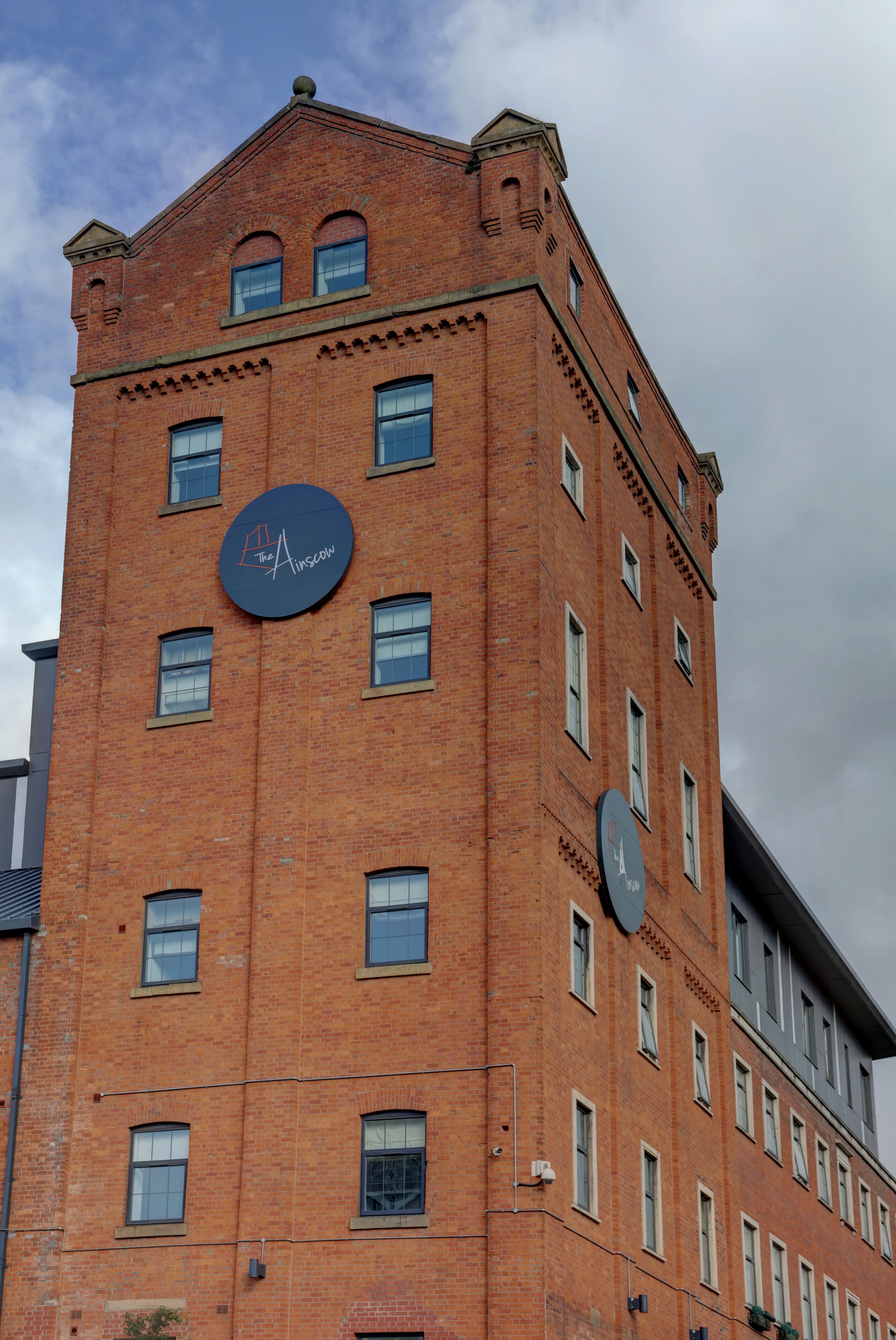 A red brick building with multiple windows and a circular sign on the facade.