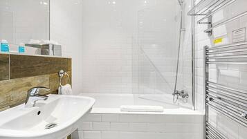 A modern bathroom with a white sink, a bathtub, and a glass shower enclosure.