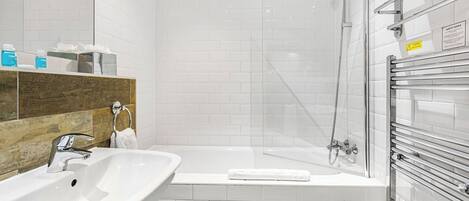 Une salle de bain moderne avec un lavabo blanc, une baignoire et une cabine de douche en verre.