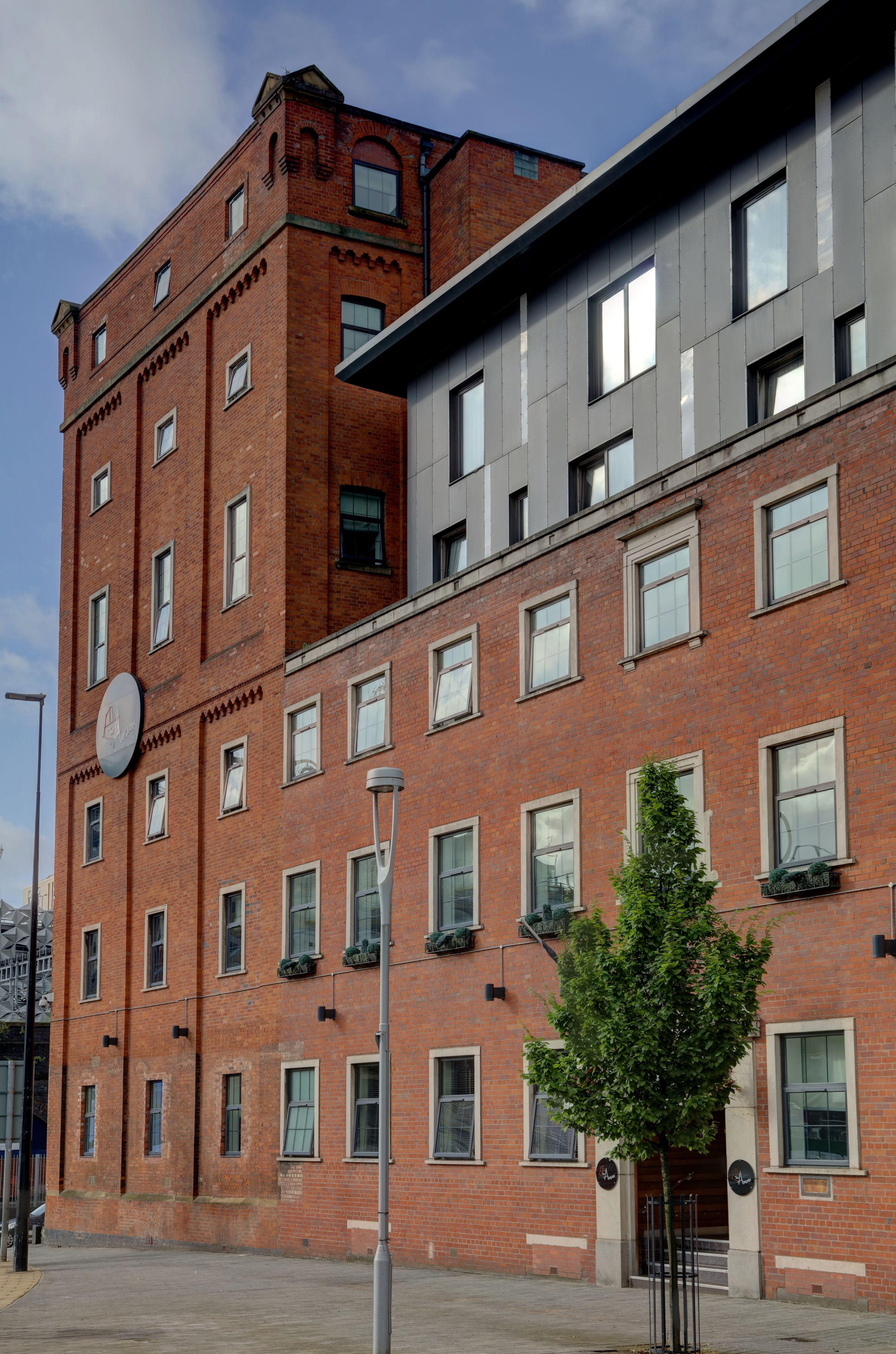 Un edificio de varios pisos con fachada de ladrillo rojo y una extensión moderna.
