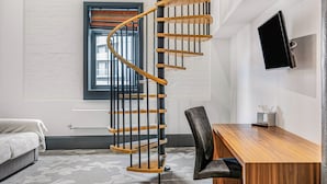 A modern room with a spiral staircase, a wooden desk, a chair, a bed, and a TV mounted on the wall. - The Ainscow Hotel (Salford)